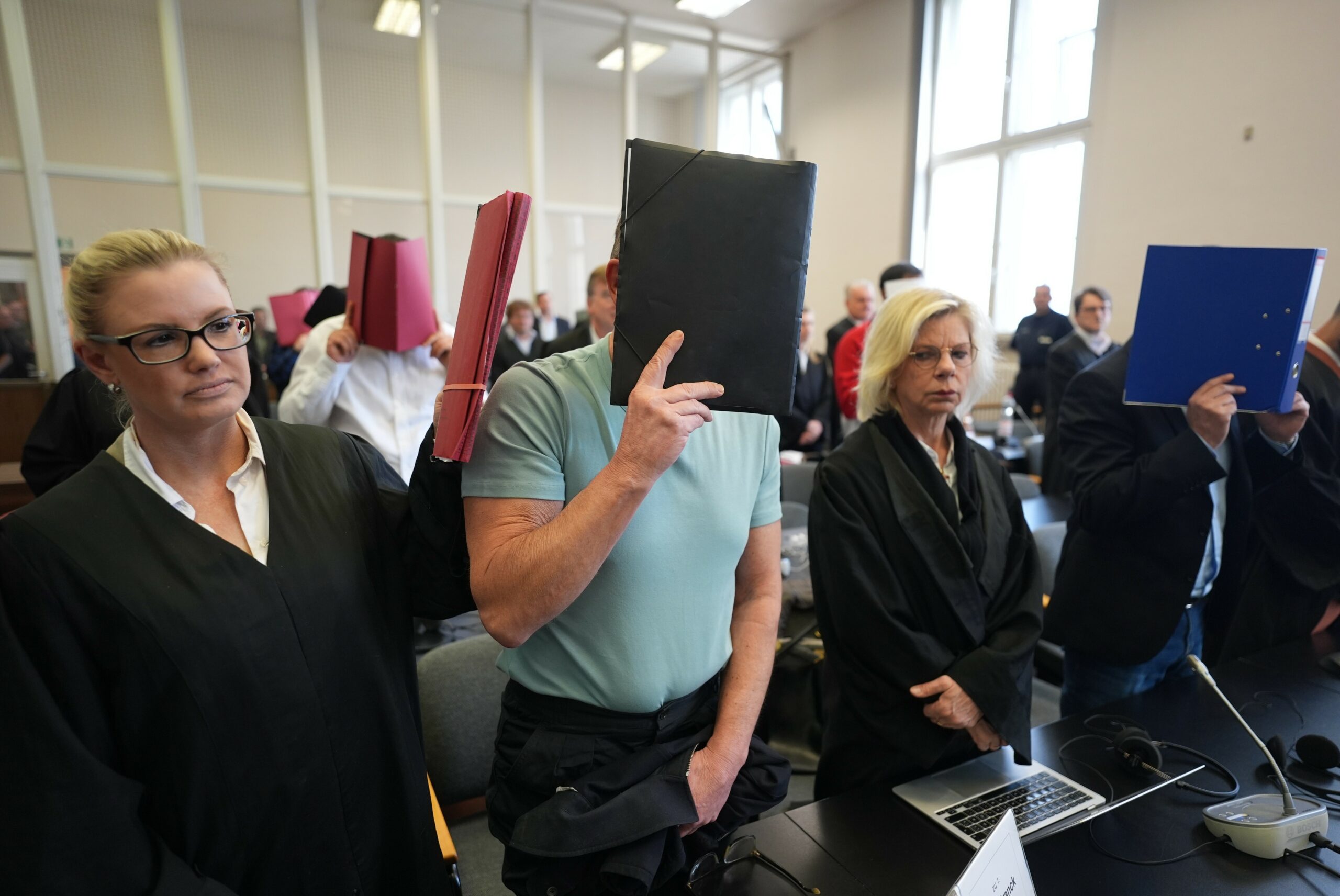 Personen mit Aktenordnern vorm Gesicht