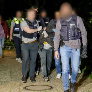 Einsatzkräfte der Polizei führen einen Tatverdächtigen nach seiner Festnahme ab.