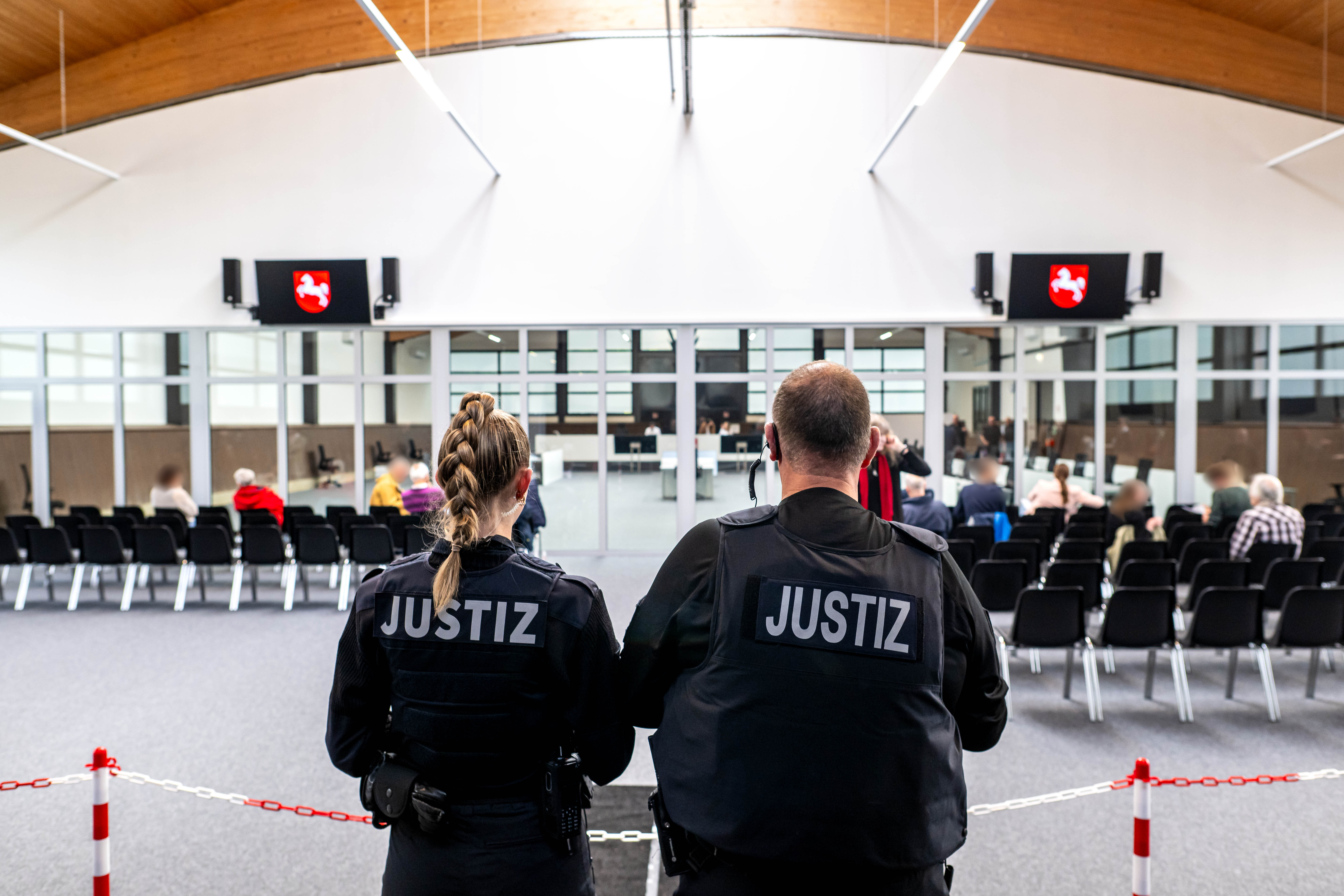 Justizbeamte stehen im Zuschauer-und Pressebereich vom Gerichtssaal. Die Verhandlung findet erstmals in einer eigens umgebauten Reithalle in Verden statt.