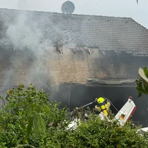 Die Feuerwehr arbeitet an der Absturzstelle, nachdem ein Flugzeug in ein Wohnhaus gestürzt ist.