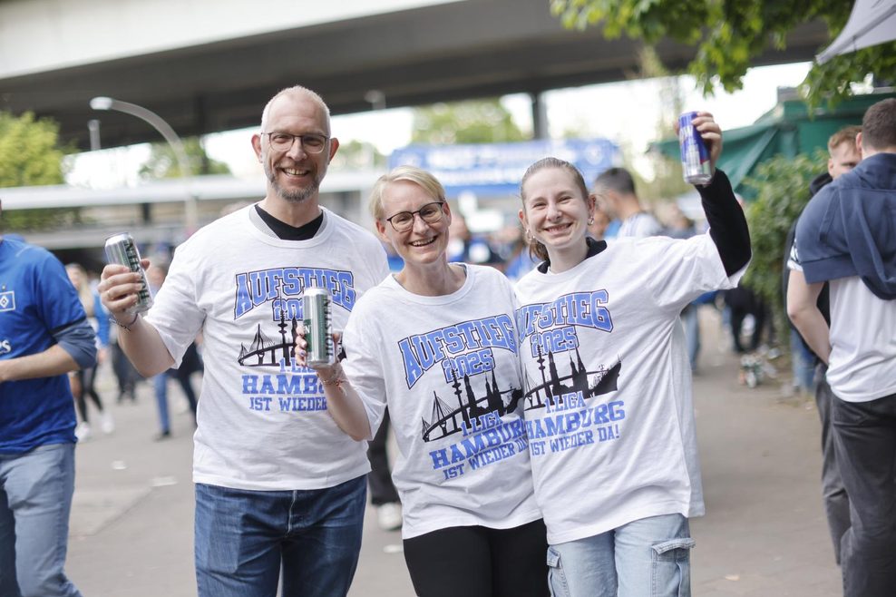 Florian (48, v.l.), Ivonne (47) und Anna (20), alle drei Dauerkarten-Inhaber aus Hamburg, haben sich Aufstiegs-T-Shirts gekauft.