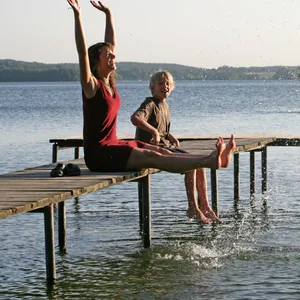 Eine Frau und ein Kind sitzen auf einem Steg am Großen Plöner See.