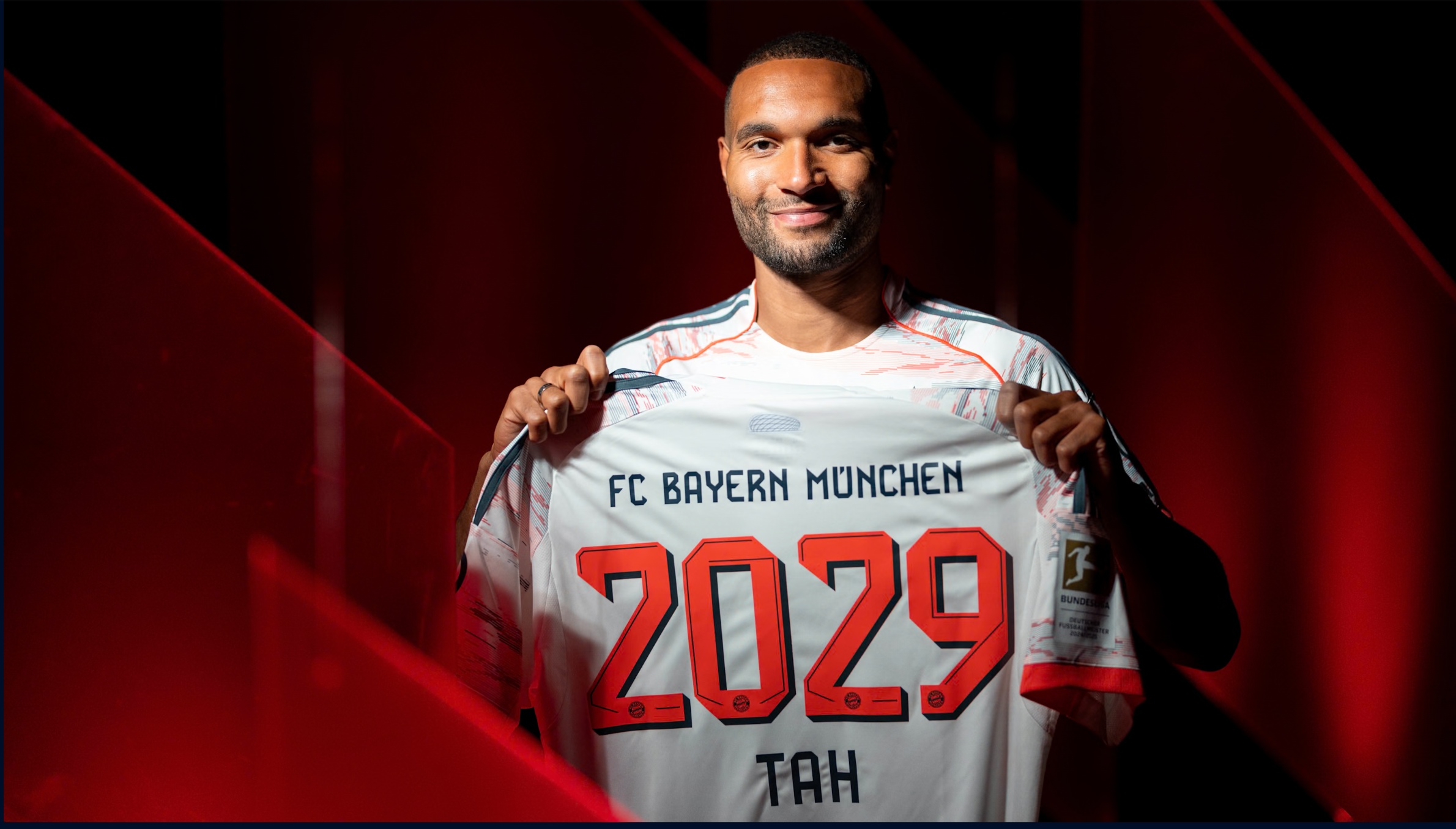 Jonathan Tah hält ein Bayern-Trikot