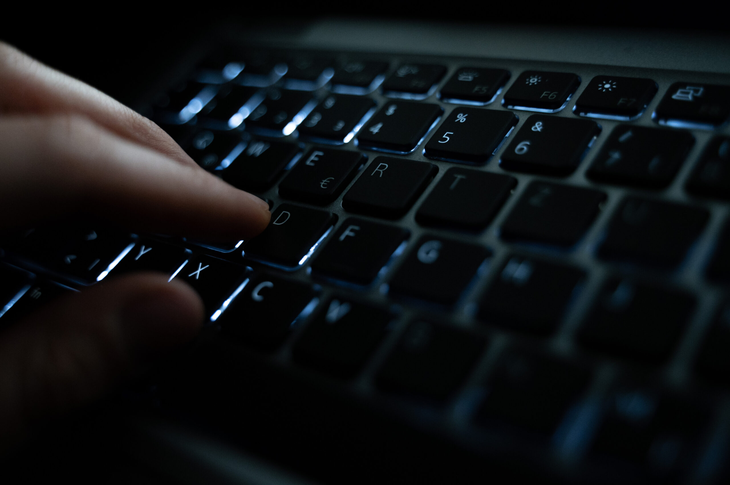 Eine Frau tippt auf die beleuchtete Tastatur eines Laptops. (Symbolbild)