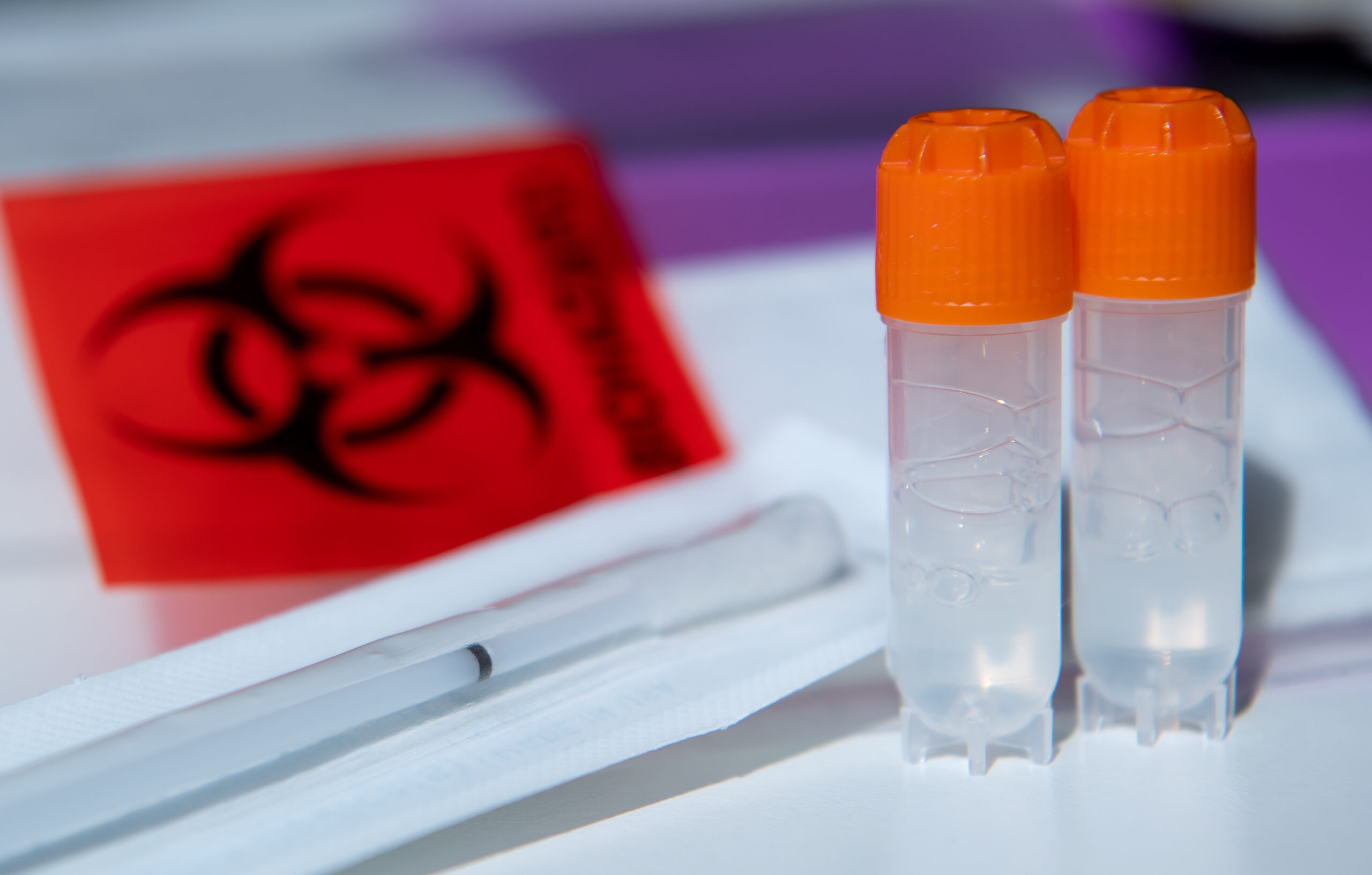 Ein Wattestäbchen und zwei Röhrchen für biologische Proben von einem DNA-Test zur Ahnenforschung stehen auf einem Tisch. (Symbolbild)