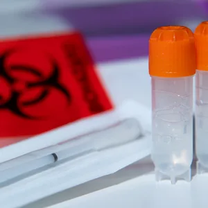 Ein Wattestäbchen und zwei Röhrchen für biologische Proben von einem DNA-Test zur Ahnenforschung stehen auf einem Tisch. (Symbolbild)
