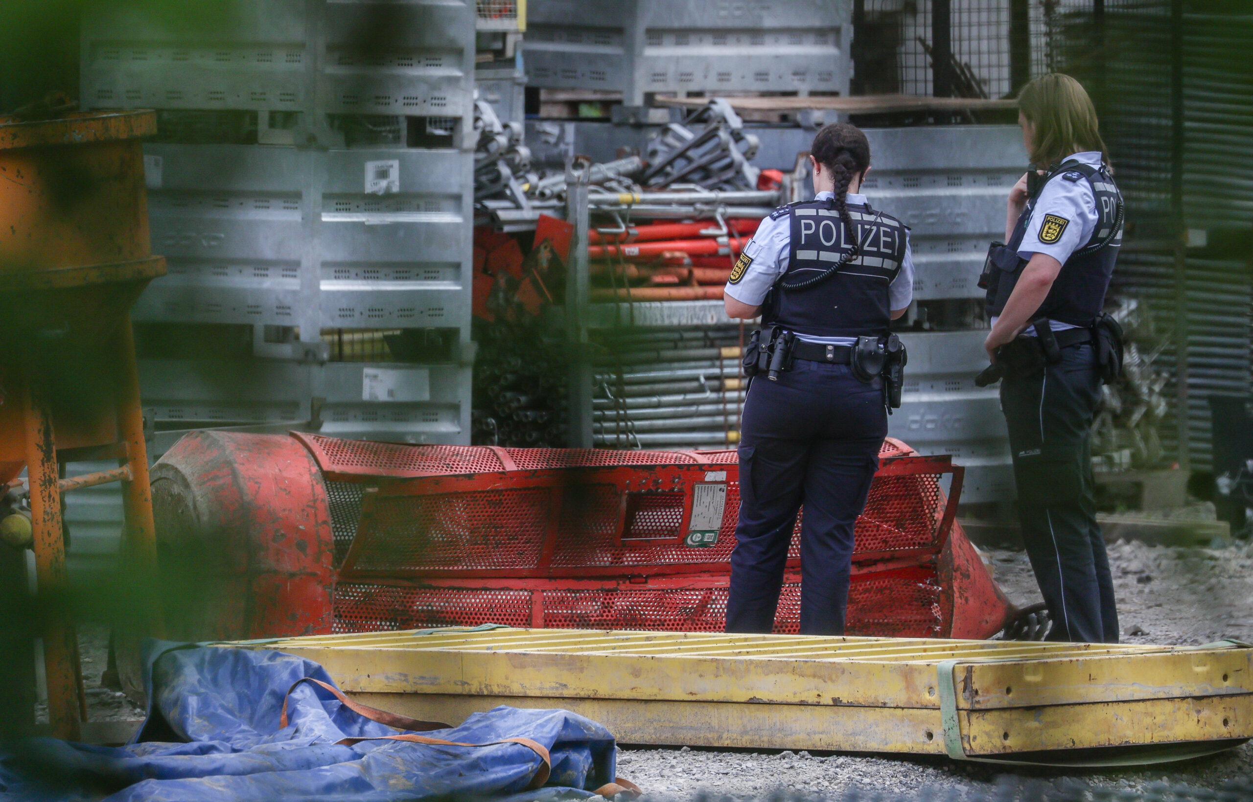 Einsatzkräfte der Polizei stehen auf der Hochbrücken-Baustelle neben einer Gondel.