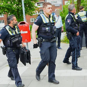 Polizisten in Lohbrügge im Einsatz. Ein Beamter (M.) versteckt die sichergestellte Waffe hinter seinem Rücken.