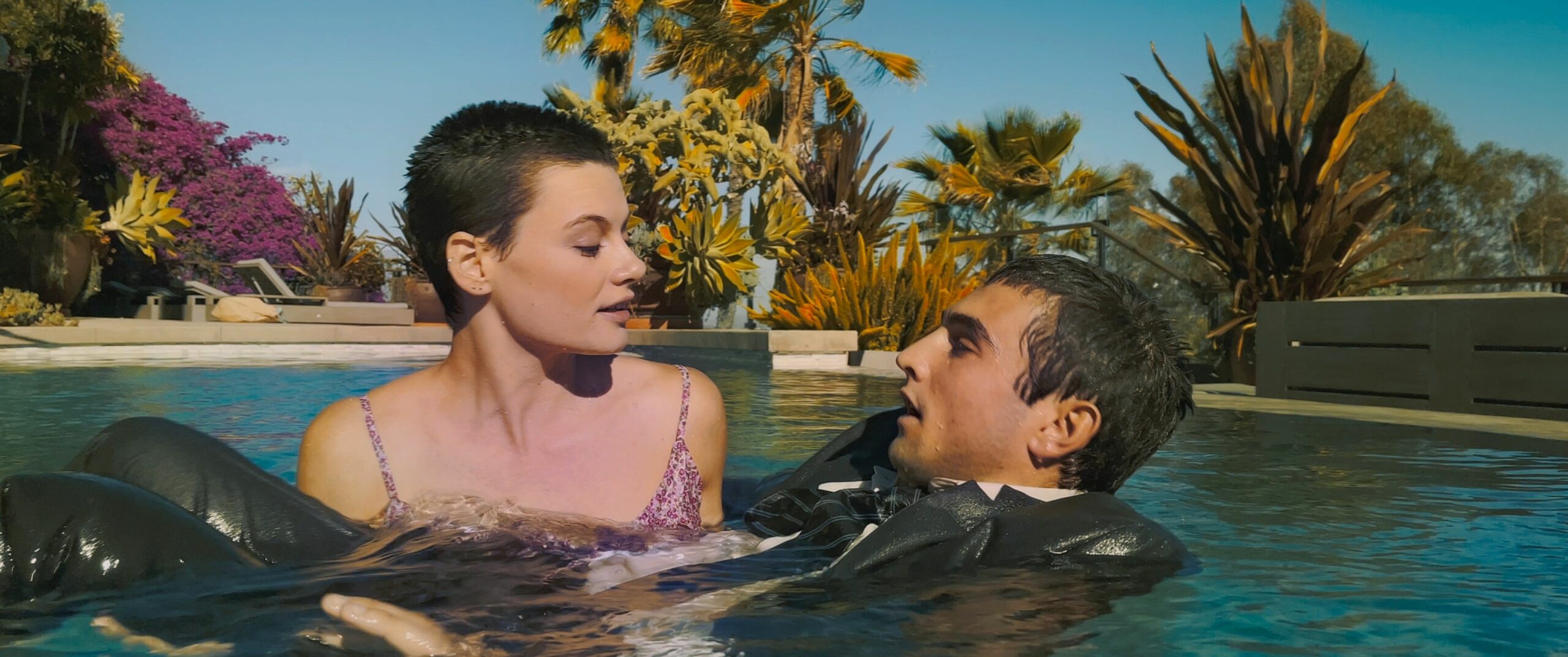 Eine Filmszene von „June And John“ zeigt eine Frau und ein Mann in einem Pool