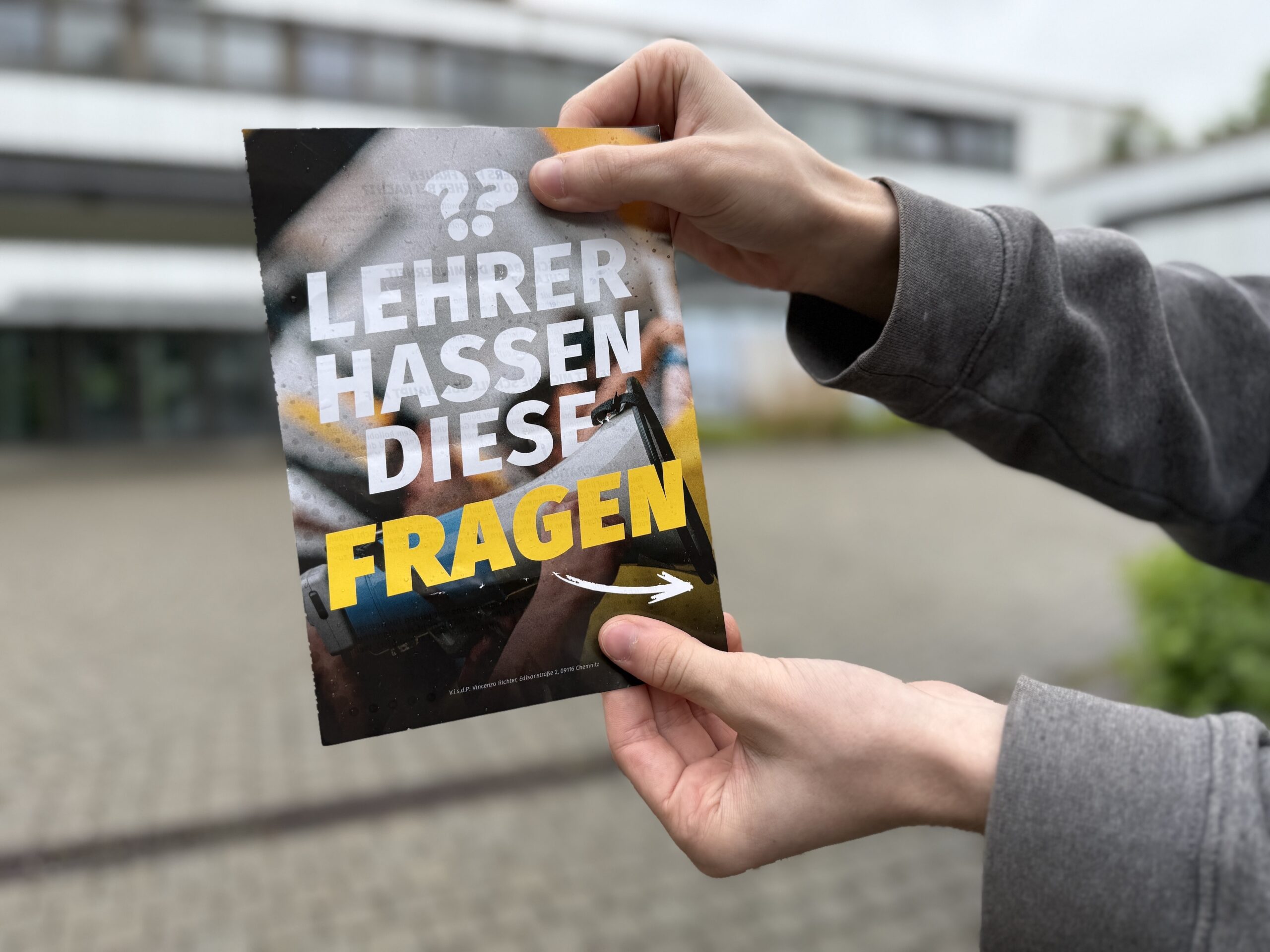 Ein Flyer, der von der Identitären Bewegung an Schulen verteilt wird, wird vor einem Gymnasium in Neu-Ulm gehalten.