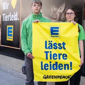 Zwei Aktivist:innen halten am „Edeka Schlemmer Markt Struve“ ein Plakat mit der Aufschrift „Edeka lässt Tiere leiden“ in die Höhe.