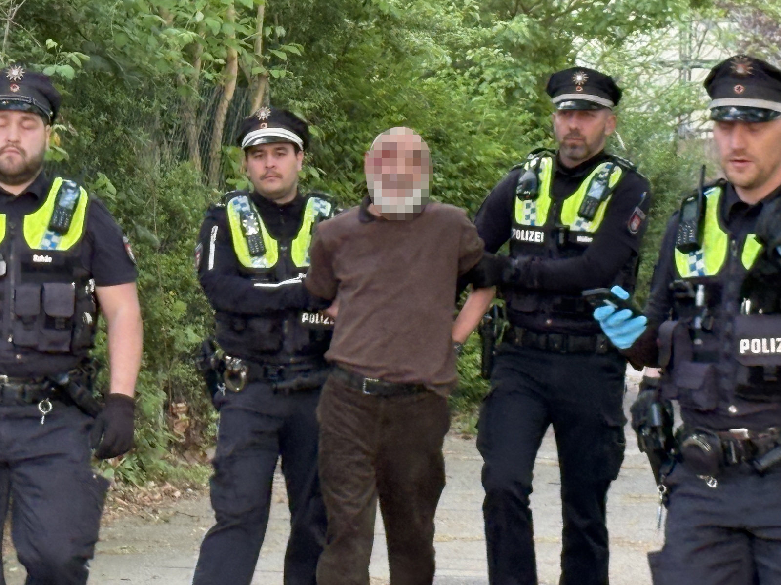 Der mutmaßliche Täter wird von Polizisten abgeführt.