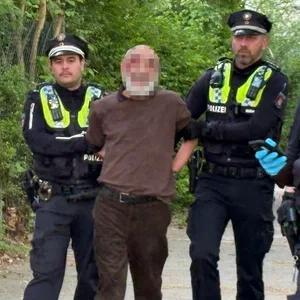 Der mutmaßliche Täter wird von Polizisten abgeführt.