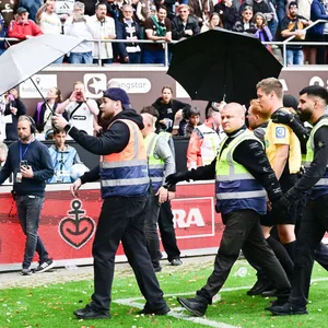 Schiedsrichter Florian Exner wird beim Abgang am Millerntor mit Regenschirmen geschützt