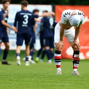 Rasmus Tobinski stützt die Hände auf die Knie und hat sich das Trikot über den Kopf gezogen