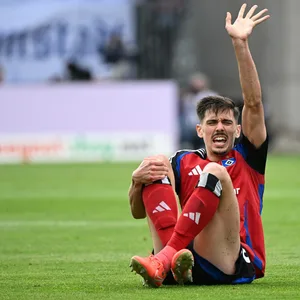 Dennis Hadzikadunic hält sich das rechte Knie und signalisiert mit der linken Hand, dass er Hilfe braucht.