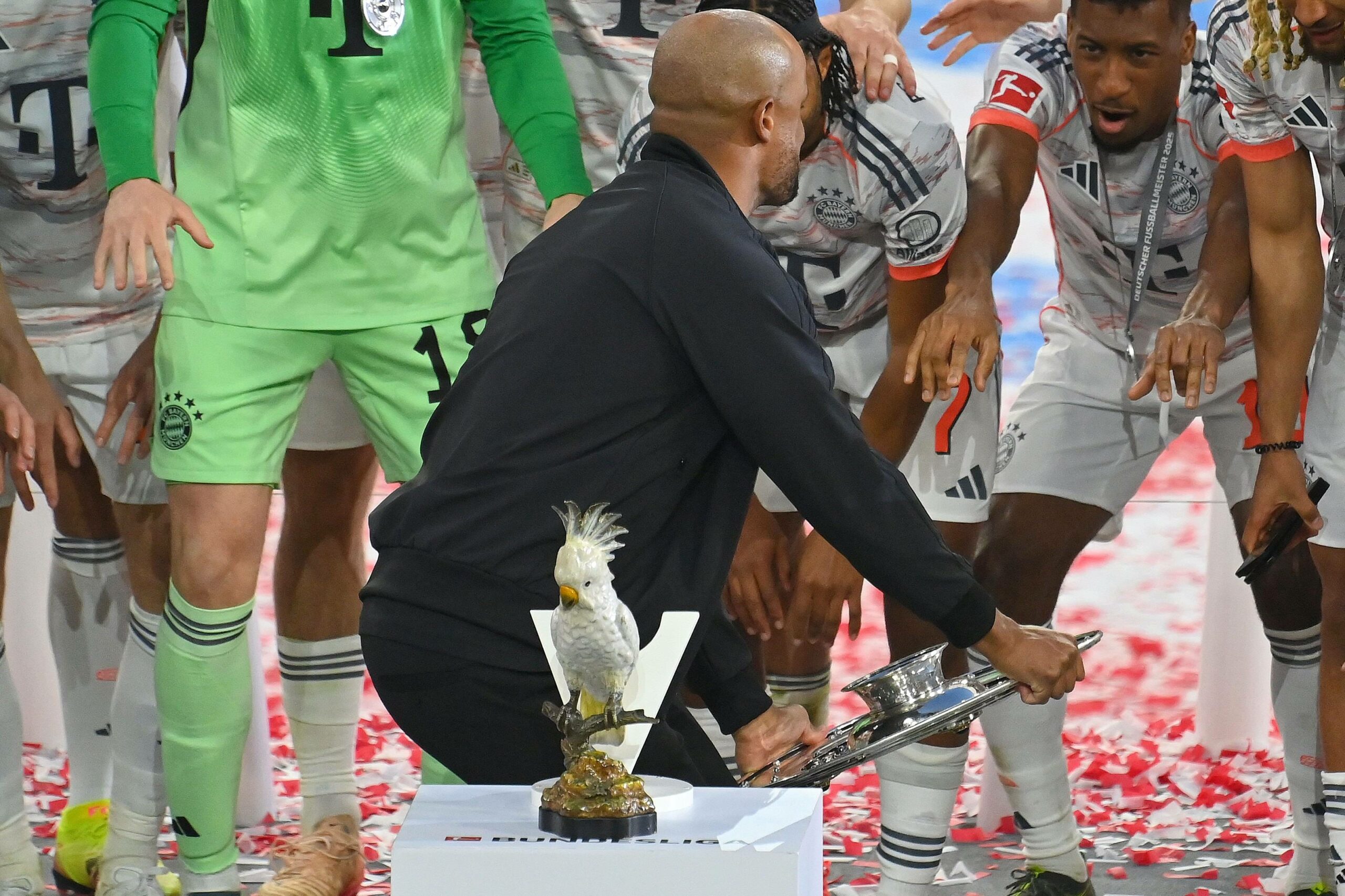 Porzellan-Kakadu steht auf dem Meisterpodest - dahinter jubelt Vincent Kompany