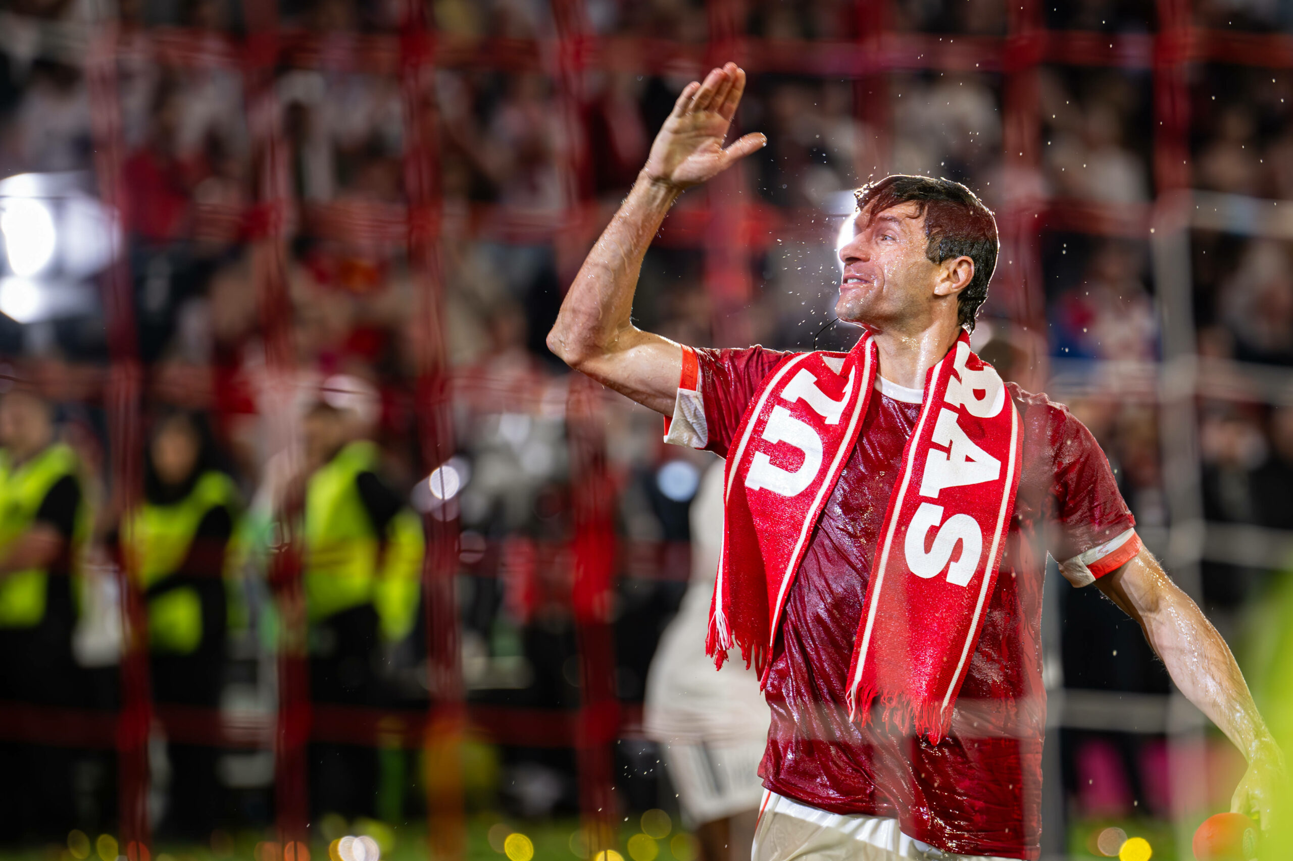 Thomas Müller feiert mit einem Schal der Bayern-Ultras