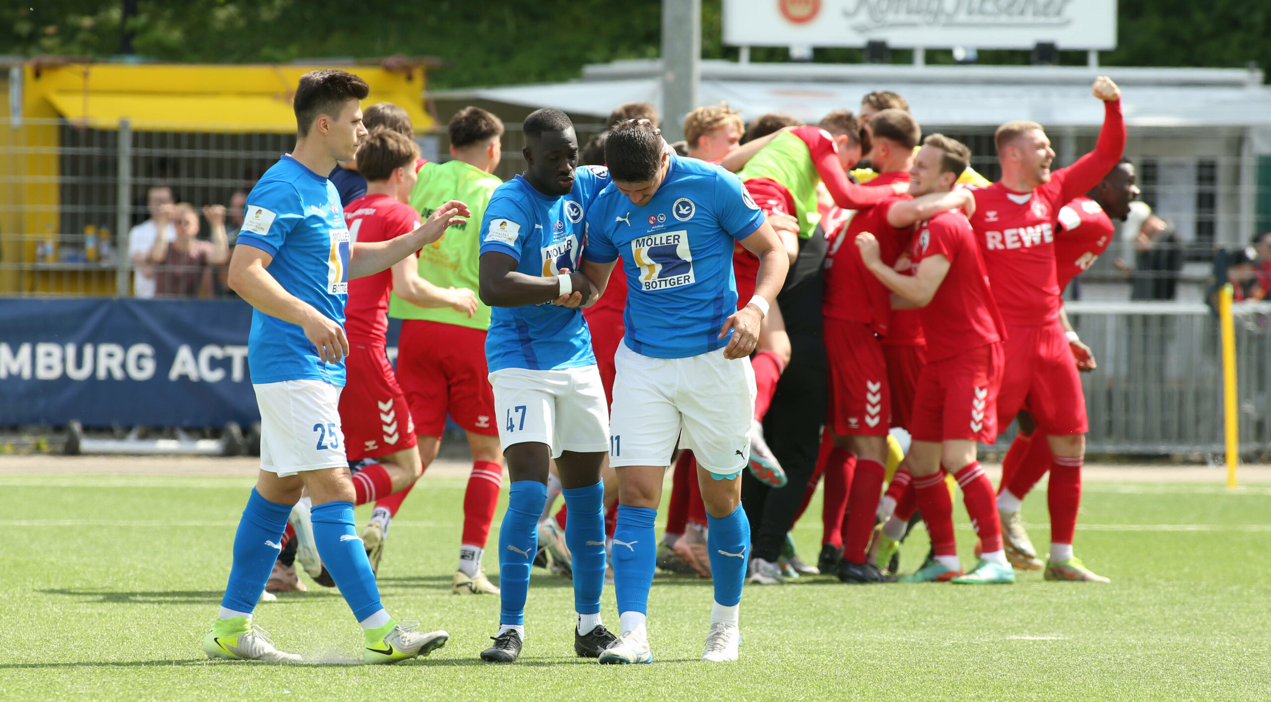 Palomas Lion Mandelkau (r.) wird nach seinem Fehlschuss im Elfmeterschießen von Fabian Jacobs und Quincy Adjei (v.l.) getröstet. Im Hintergrund jubelt Norderstedt.