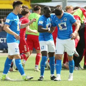 Palomas Lion Mandelkau (r.) wird nach seinem Fehlschuss im Elfmeterschießen von Fabian Jacobs und Quincy Adjei (v.l.) getröstet. Im Hintergrund jubelt Norderstedt.