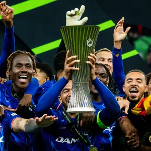 Reece James hebt die Conference League Trophäe in die Luft und seine Mitspieler jubeln mit.