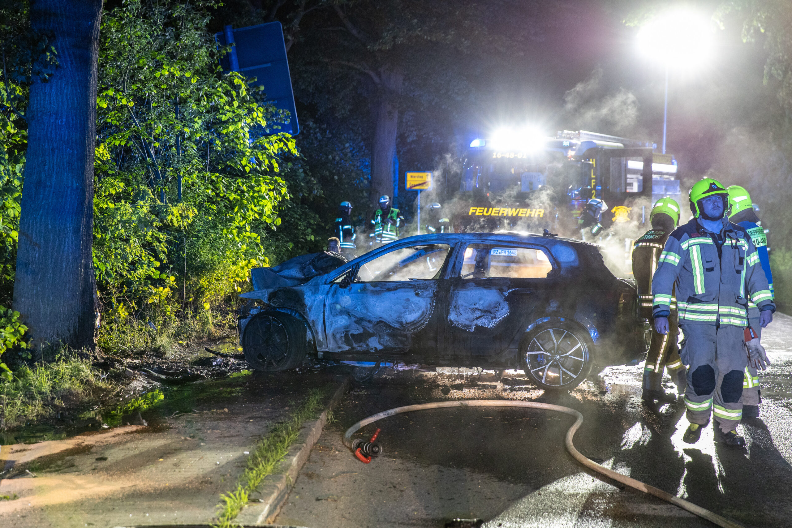 Feuerwehrkräft an ausgebranntem Wrack
