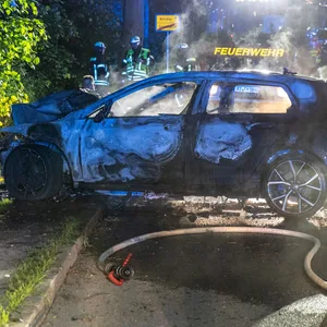 Feuerwehrkräft an ausgebranntem Wrack