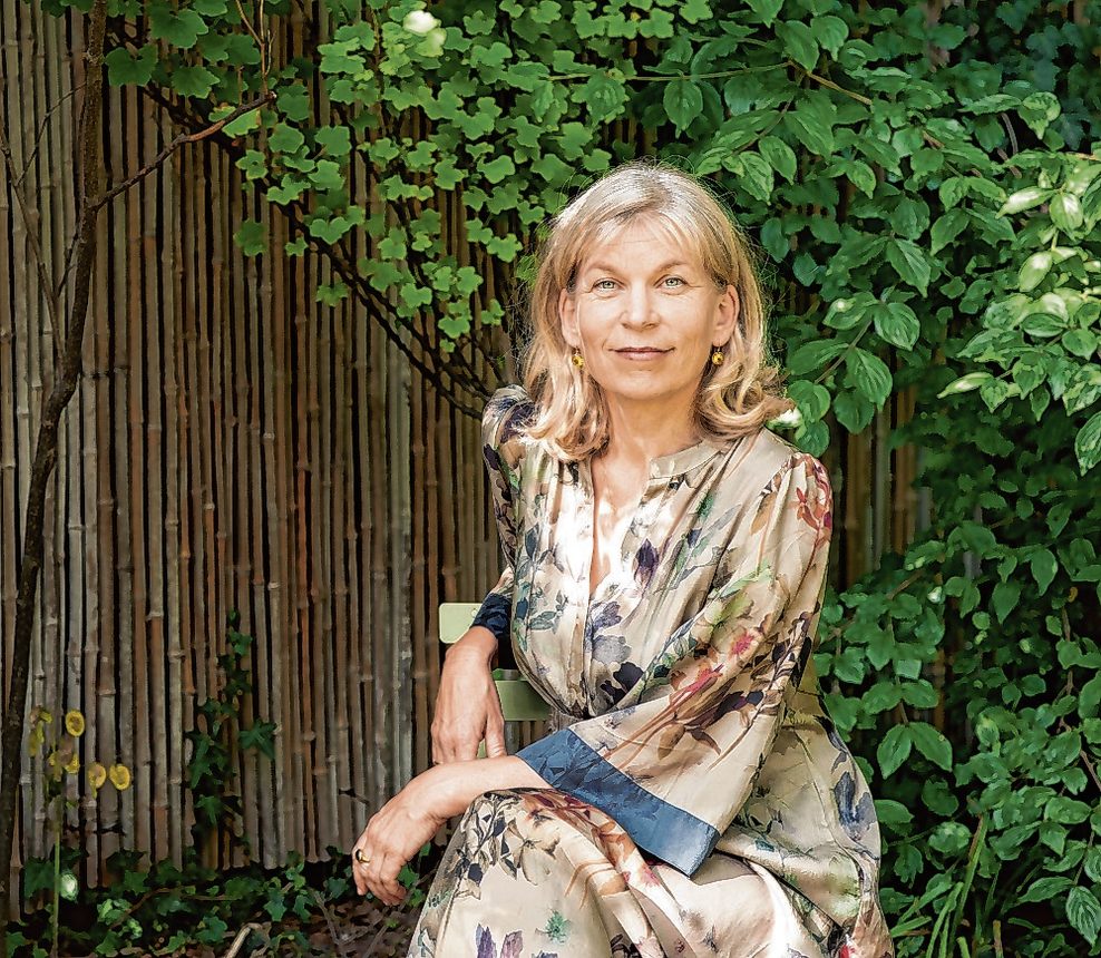 Katharina Hagena sitzt auf einem Stuhl in einem Garten.