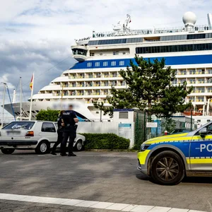 Ein Polizeiauto vor einem Kreuzfahrtschiff (Symbolbild).