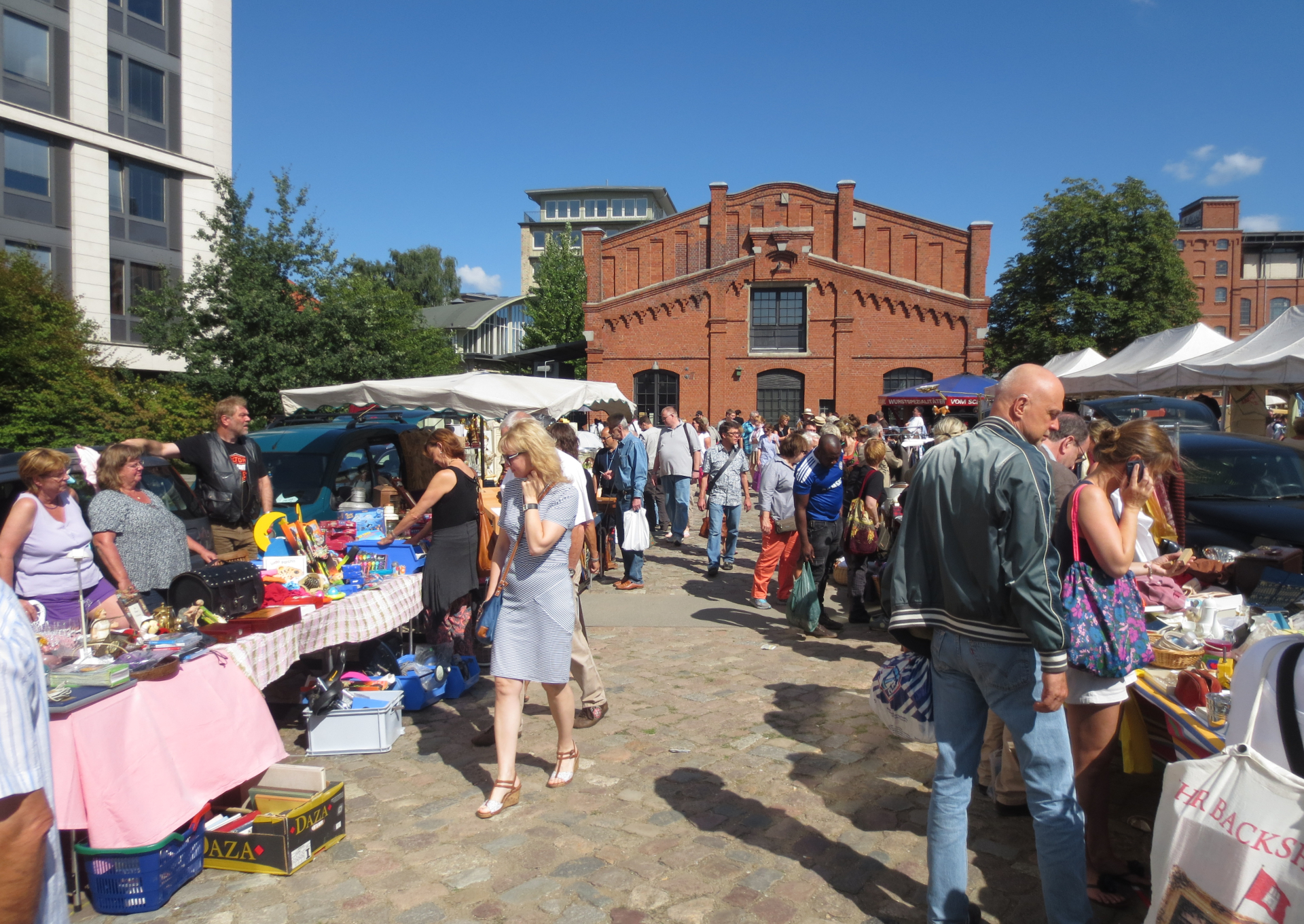 Menschen stehen an Flohmarktständen.
