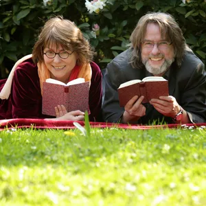 Vera Rosenbusch und Lutz Flörke liegen mit Büchern in der Hand auf einer Wiese.