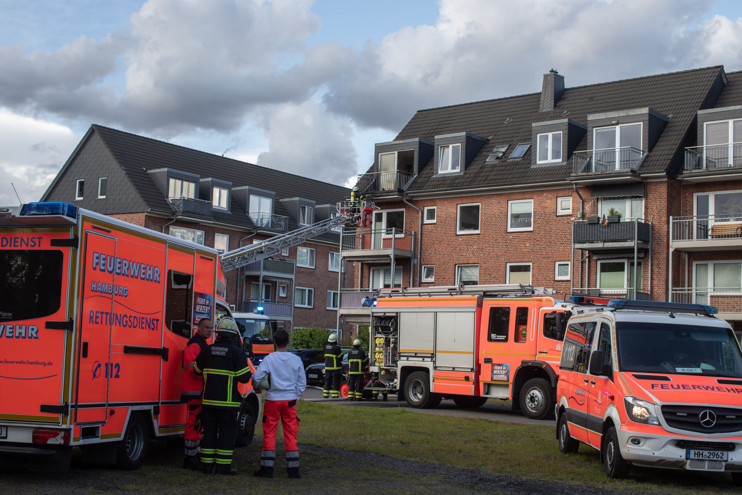 Mehrere Feuerwehrautos stehen vor einem Gebäude. Der Kran eines Autos ist ausgefahren.