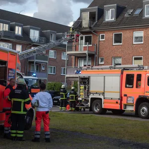 Mehrere Feuerwehrautos stehen vor einem Gebäude. Der Kran eines Autos ist ausgefahren.