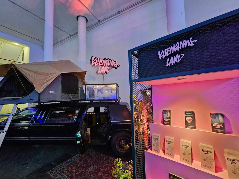 Eine Schwarze Stretchlimo mit Dachzelt-Aufbau steht vor dem Stand des „Kliemannslands“ auf der OMR 2025.