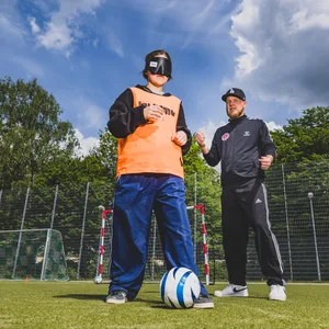 St. Paulis Blindenfußballer Viktor Faul erklärt Schülerin Vida, wie sich der Ball auch verdunkelt spielen lässt.