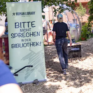 Die Human Library Hamburg bei der Eröffnung des Trinitatis Quartiers in Altona. Viele kleine Tische und Stühle, auf denen Menschen sitzen.