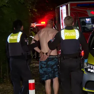 Polizisten führen einen Tatverdächtigen in Stellingen ab.