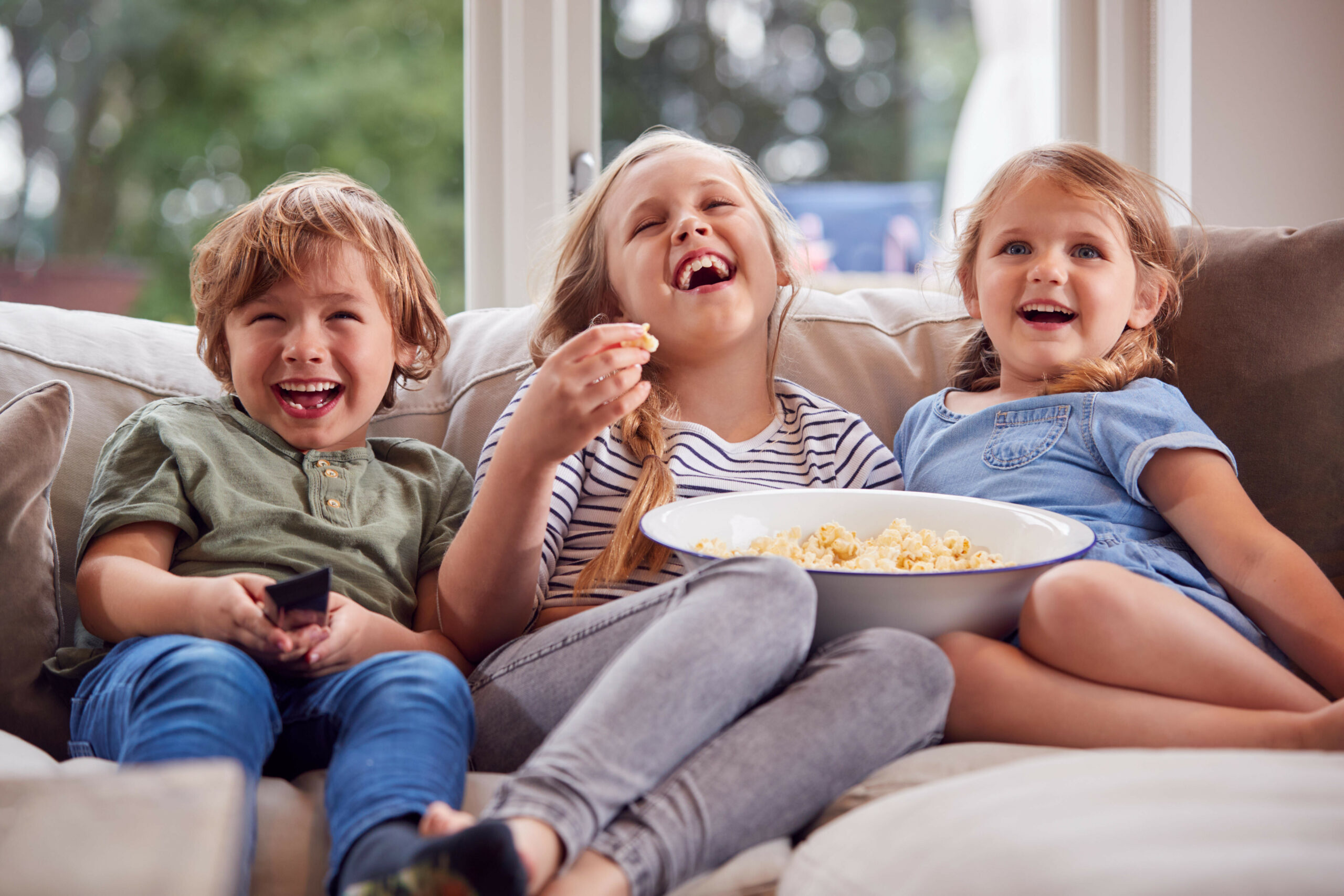 Drei Kinder sitzen auf einem Sofa.