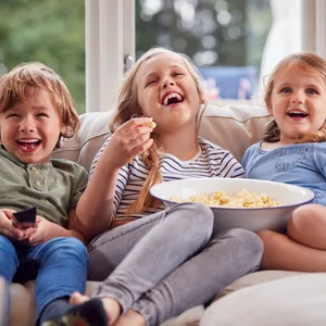 Drei Kinder sitzen auf einem Sofa.