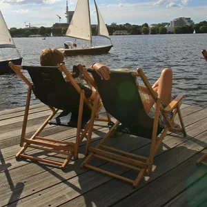 Menschen sonnen sich an der Alster.