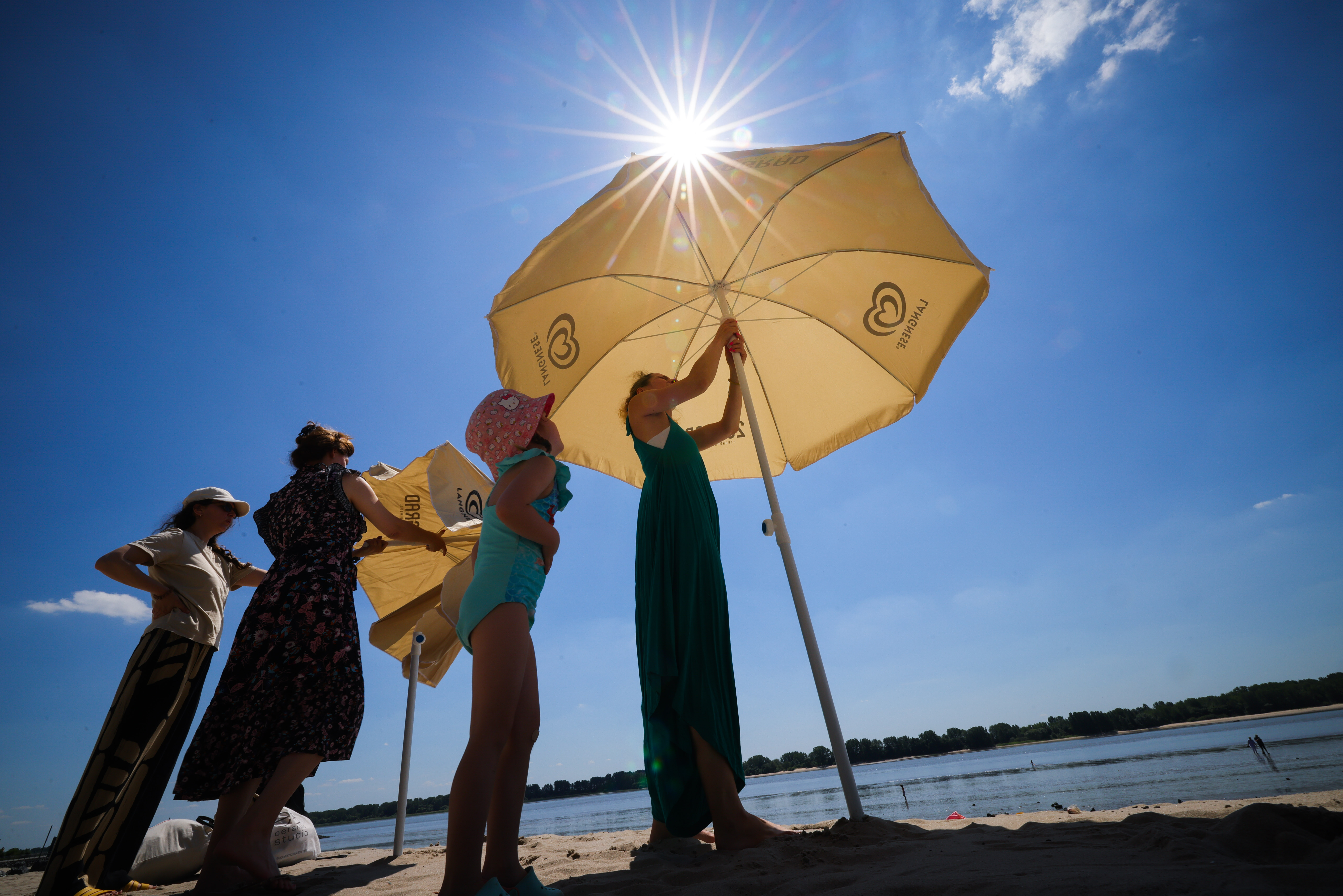 Menschen mit Sonnenschirm am Strand