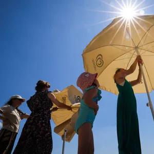 Menschen mit Sonnenschirm am Strand