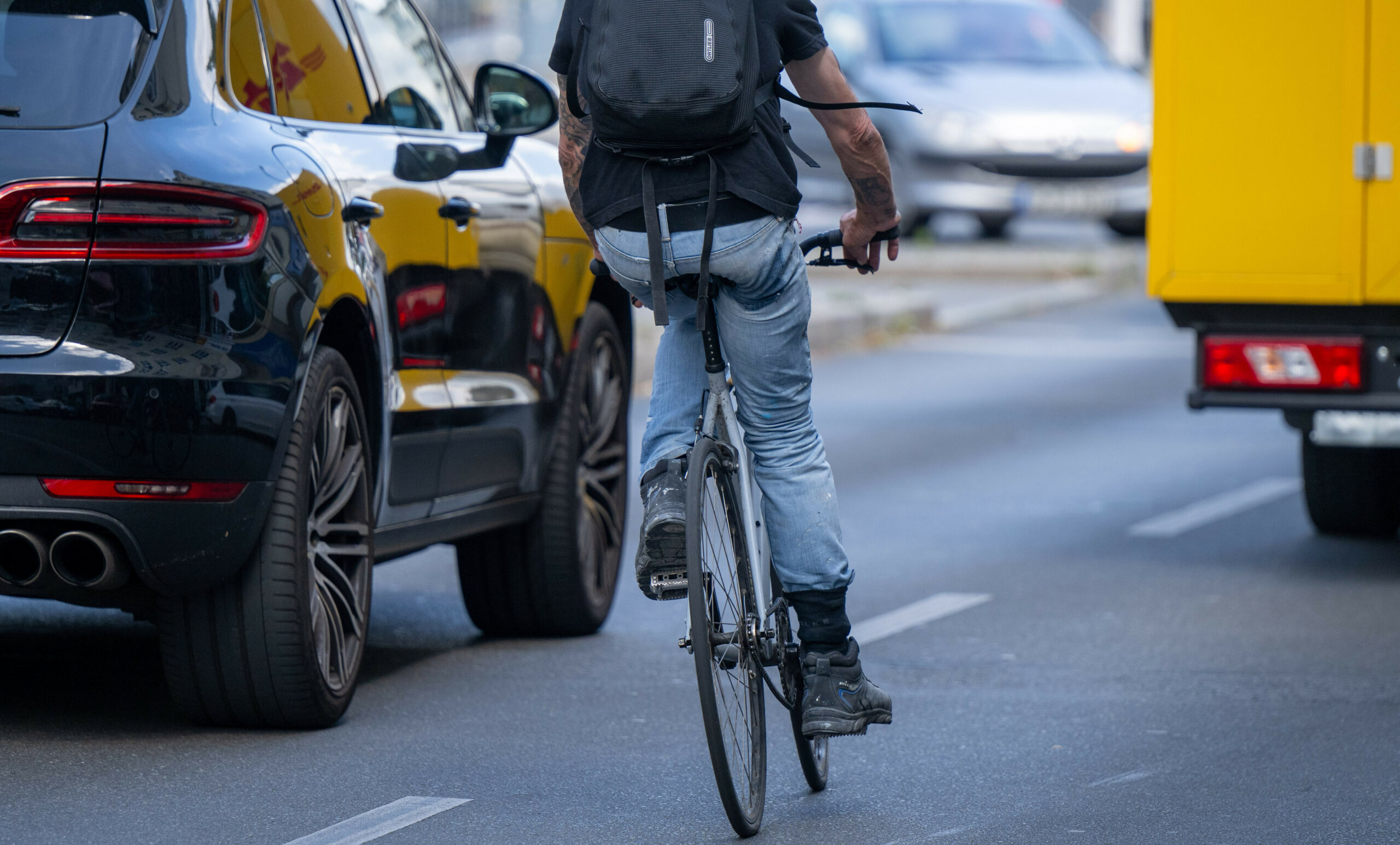 Ein Radfahrer fährt neben einem Auto auf der Straße.