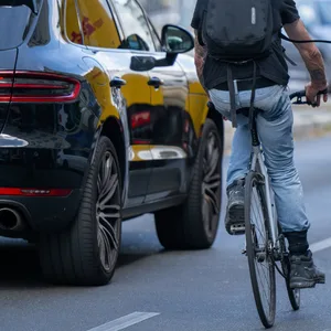 Ein Radfahrer fährt neben einem Auto auf der Straße.