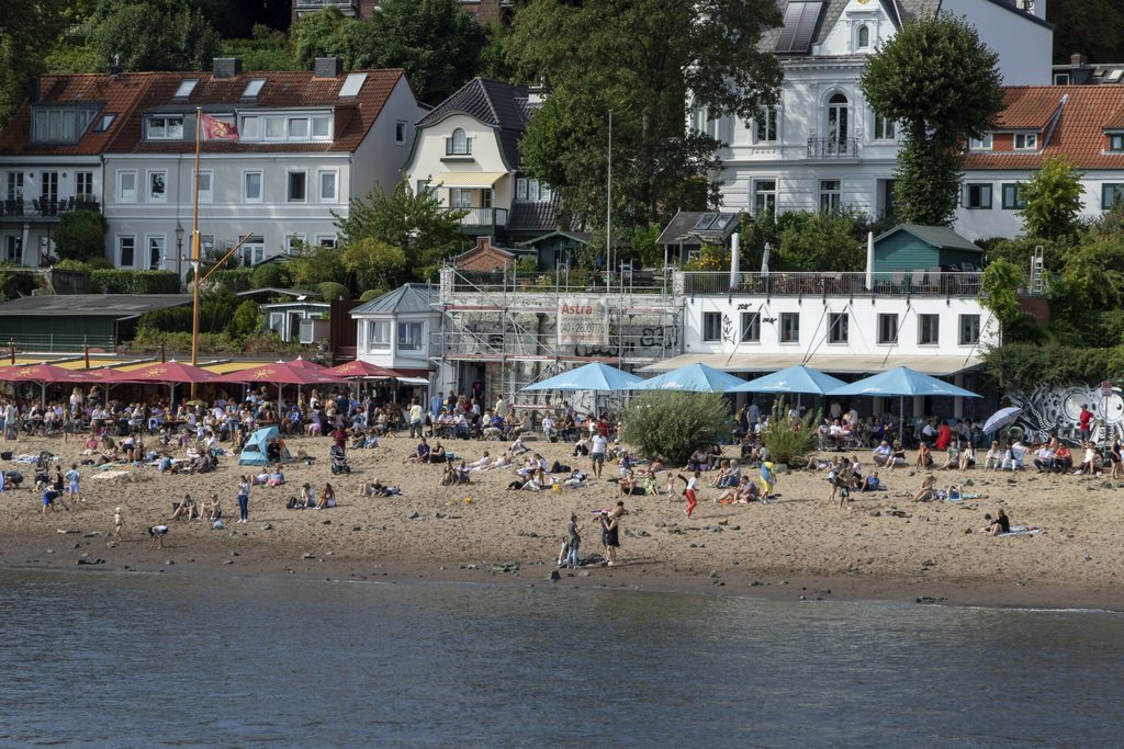 Menschen baden in der Elbe vor den Restaurants Strandperle und Ahoi Strandkiosk am Elbstrand Oevelgönne, Hamburg. (Symbolbild)