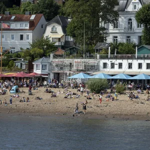 Menschen baden in der Elbe vor den Restaurants Strandperle und Ahoi Strandkiosk am Elbstrand Oevelgönne, Hamburg. (Symbolbild)