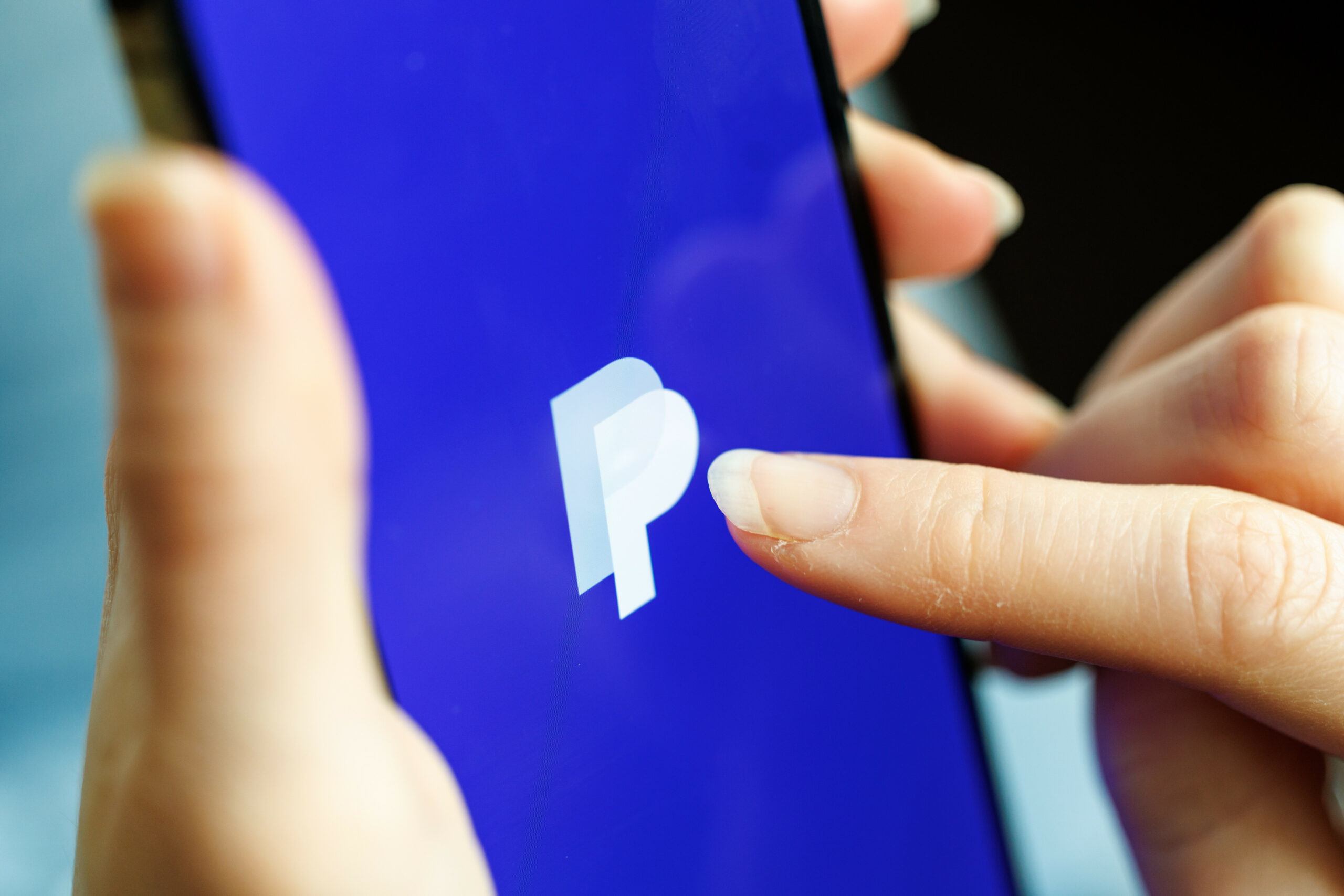 Eine Frau hält ein Smartphone mit der Paypal-App in der Hand.