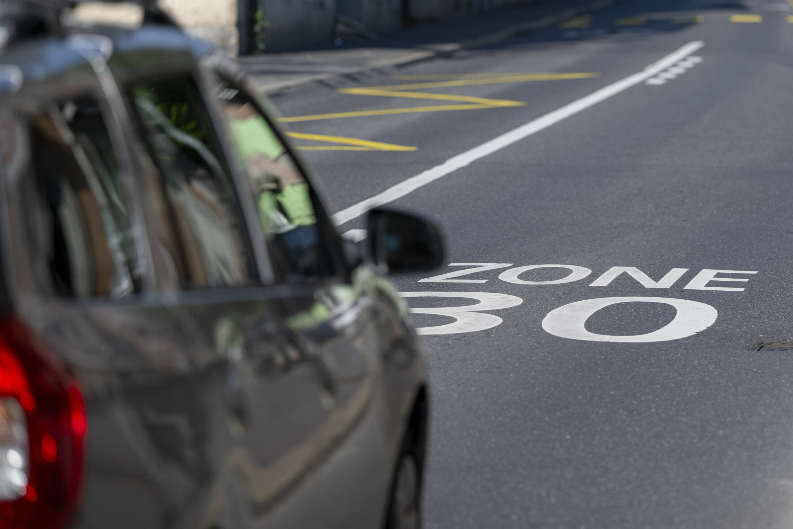 Auto fährt auf Straße mit Aufschrift „Tempo 30“.