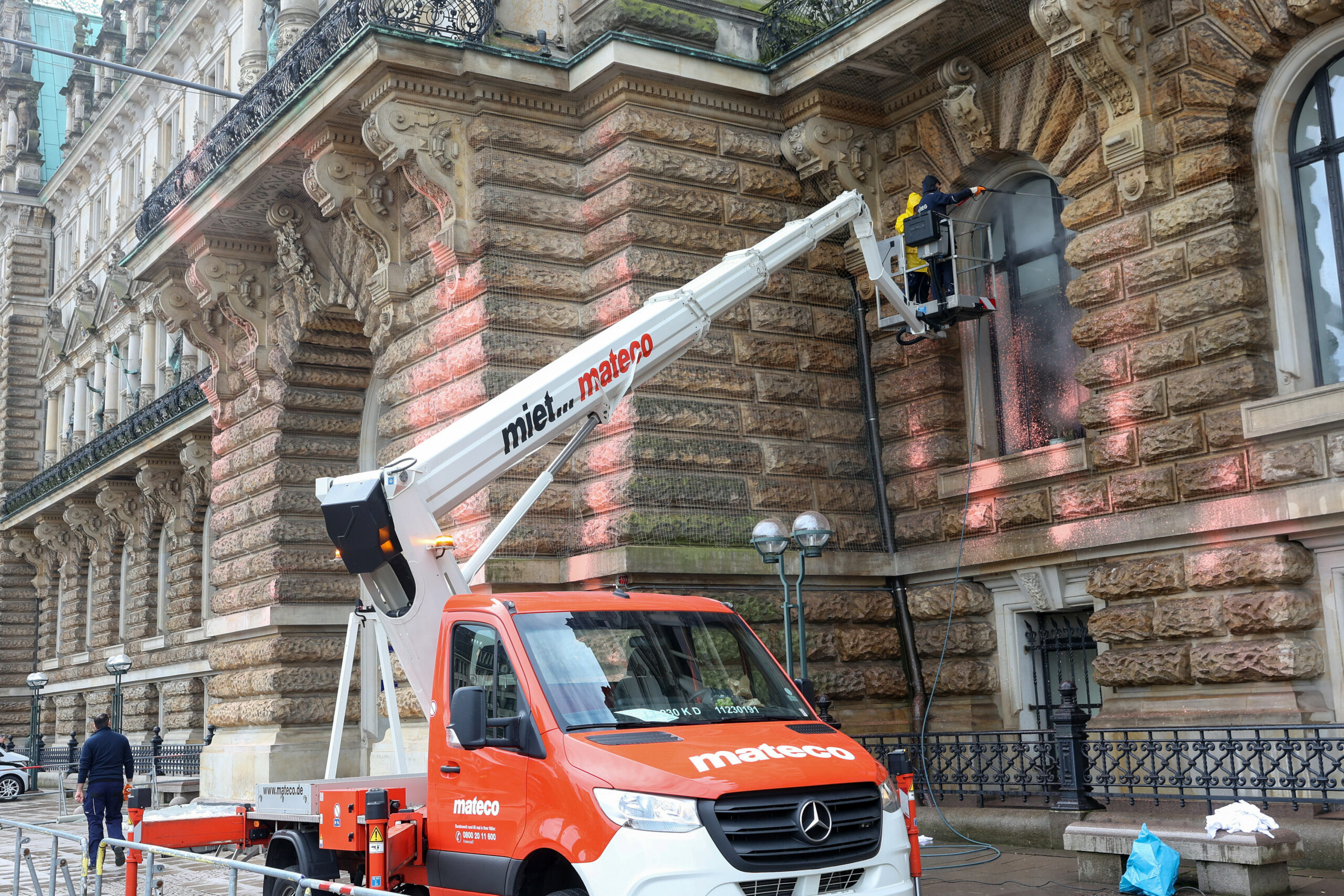 Mit einem Dampfstrahler wird die Fassade des Hamburger Rathauses gereinigt. Einen Tag vor dem Hamburg-Besuch des britischen Königs Charles III. und seiner Frau Camilla haben Klimaaktivisten der Bewegung Letzte Generation das Rathaus mit orangener Farbe besprüht.