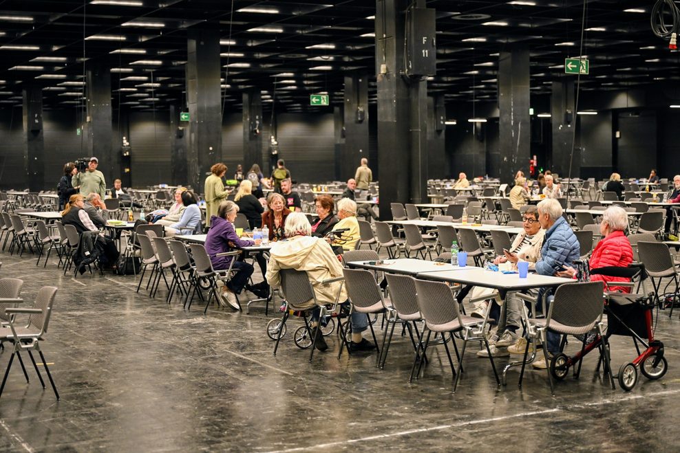 Menschen warten in der Anlaufstelle der Stadt Köln in einer Messehalle auf da Ende der Bombenentschärfung.